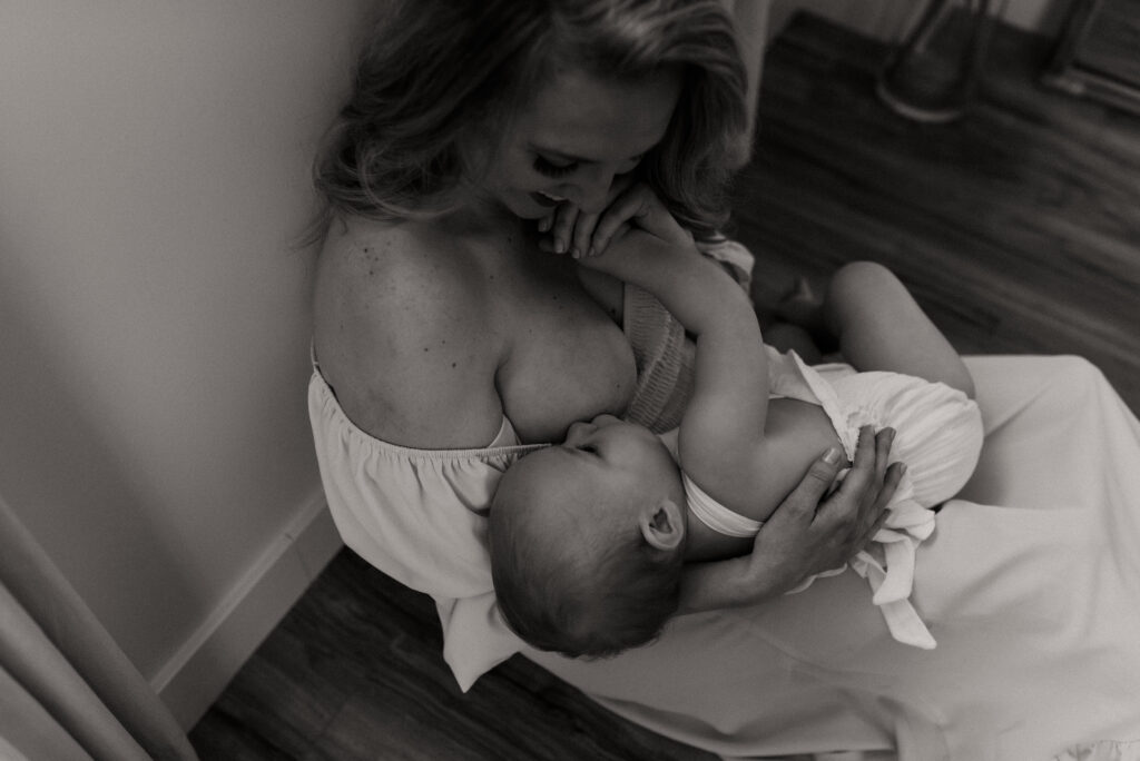 mother nursing her baby while sitting on the floor during newborn photoshoot with best newborn photographer Edmonton