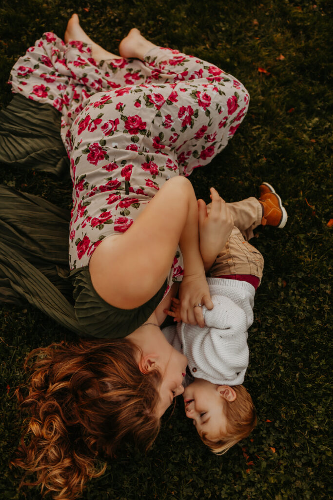 mom and toddler snuggle on the grass during a family photo shoot in Edmonton