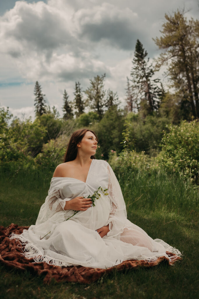 Pregnant woman in ethereal white lace dress poses for dreamy maternity photos in Edmonton