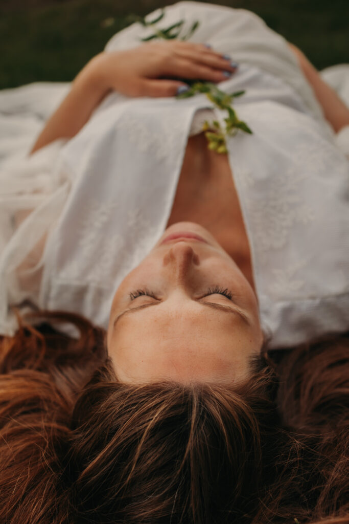 Pregnant woman in ethereal white lace dress poses for dreamy maternity photos in Edmonton with Edmonton maternity photographer