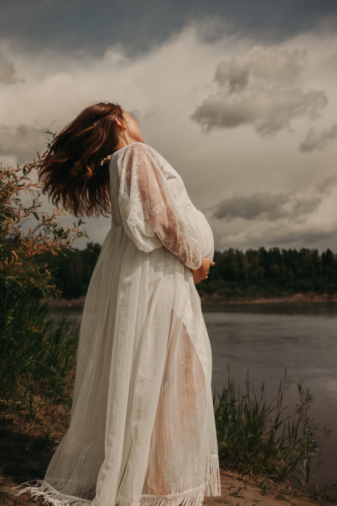 Pregnant woman in ethereal white lace dress poses for dreamy maternity photos in Edmonton with Edmonton maternity photographer