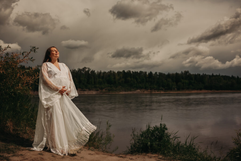 Pregnant woman in ethereal white lace dress poses for dreamy maternity photos in Edmonton with Edmonton maternity photographer