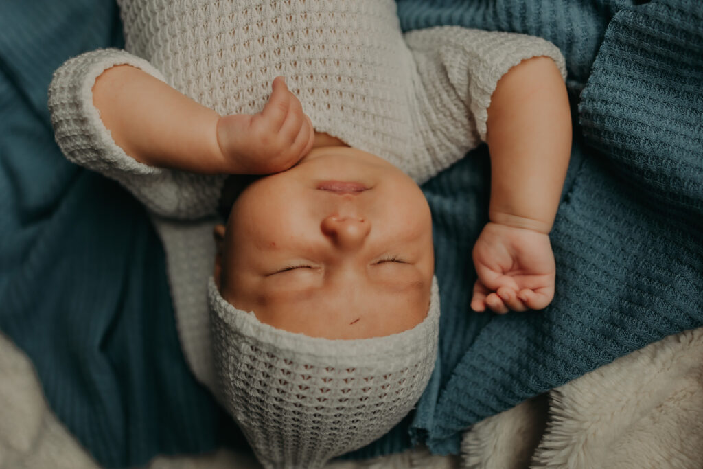 sleeping newborn baby wearing a white knit cap and romper during a newborn photo session in Edmonton 