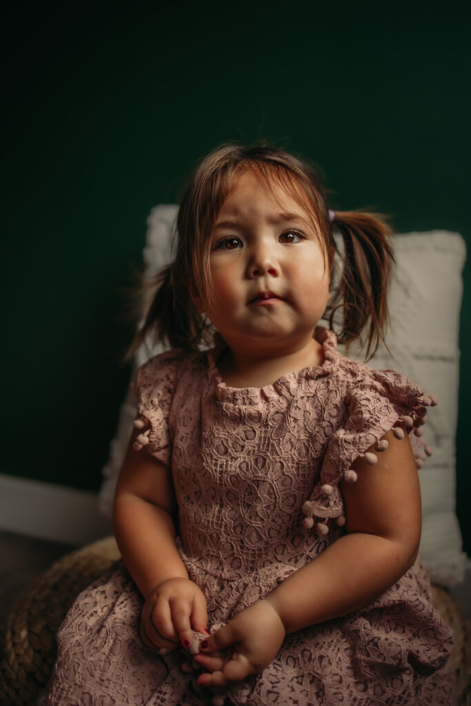 a toddler girl looks at the camera during her indoor family photo session in Edmonton, Alberta