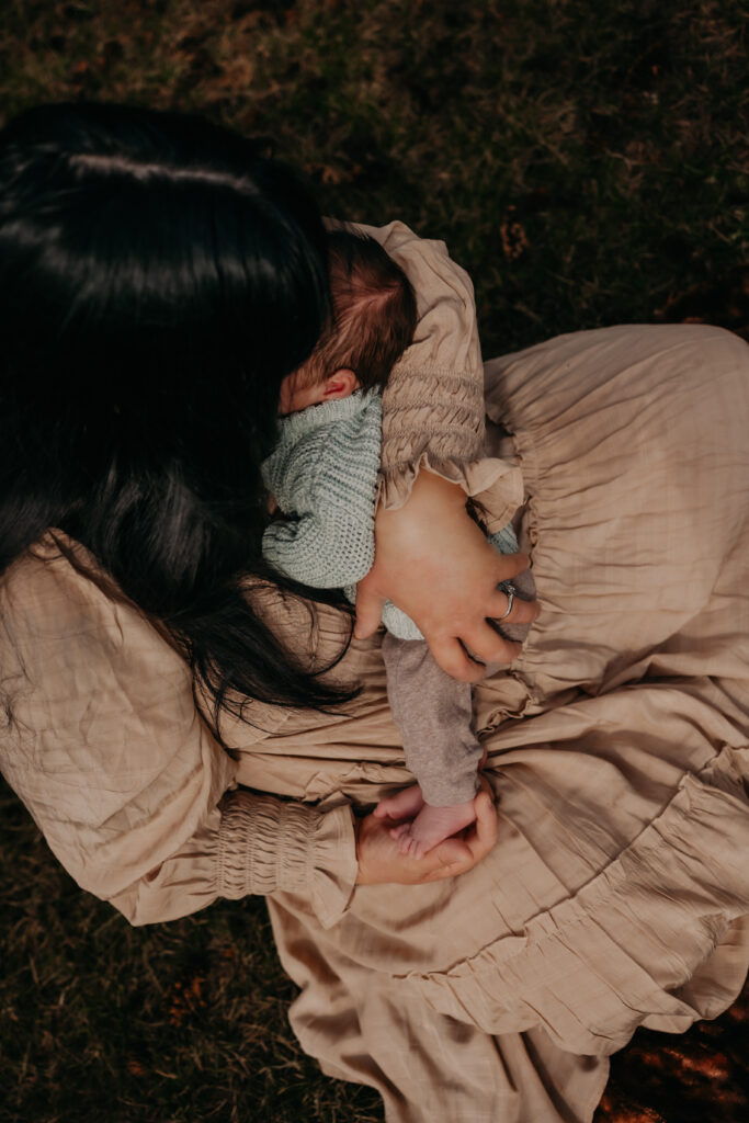 mom cuddles her newborn baby during outdoor Edmonton newborn photo shoot