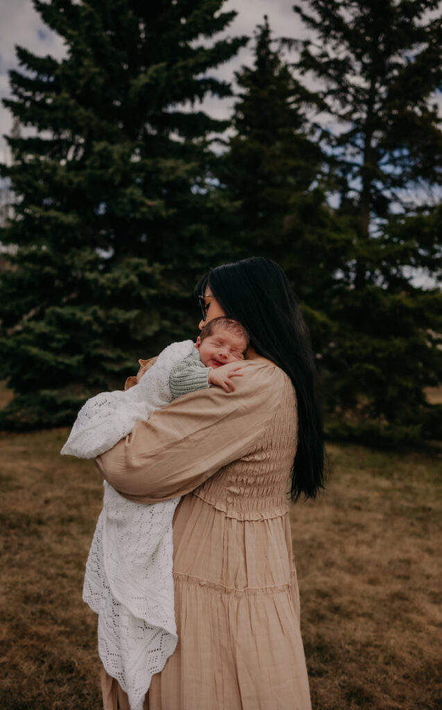 mom cuddles her newborn baby during outdoor Edmonton newborn photo session
