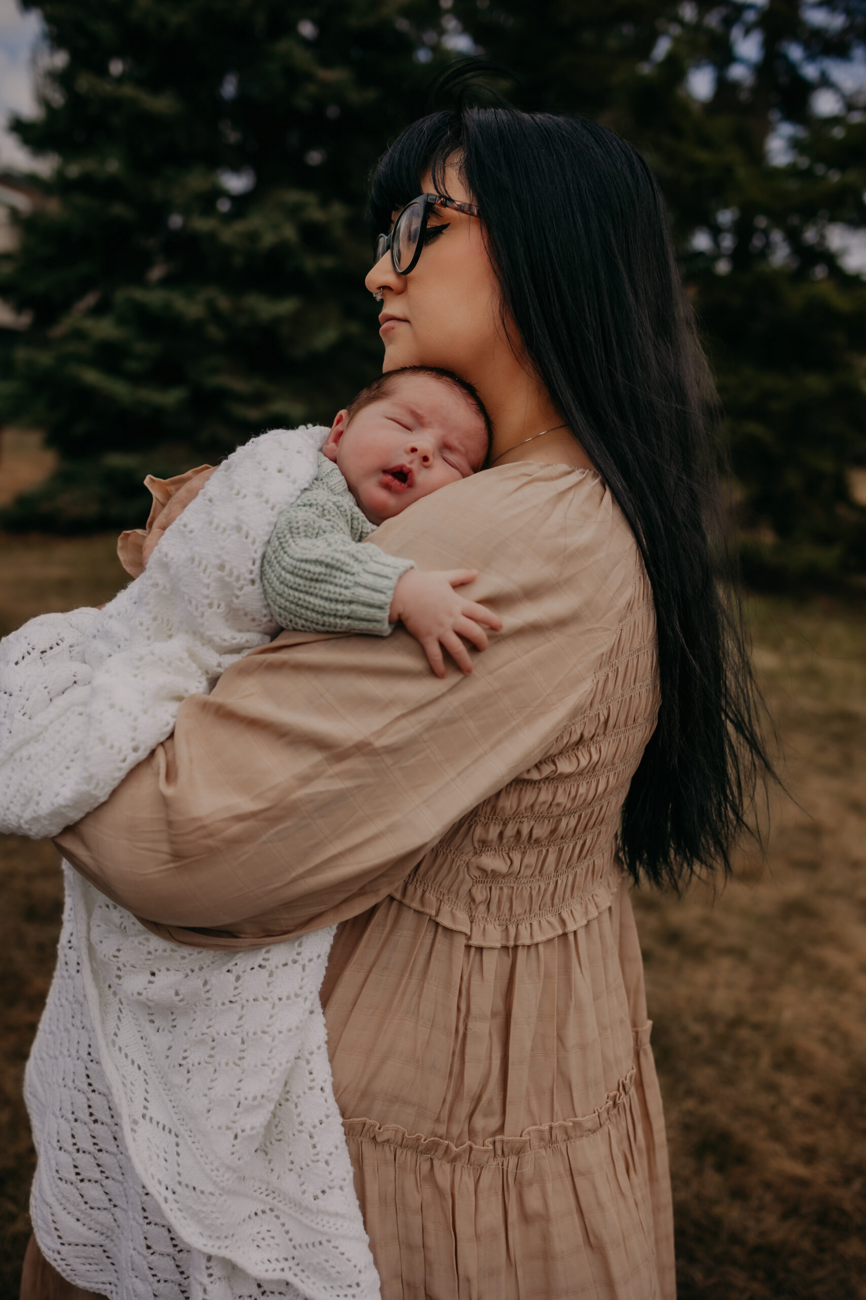 mom cuddles her newborn baby during outdoor Edmonton newborn photos