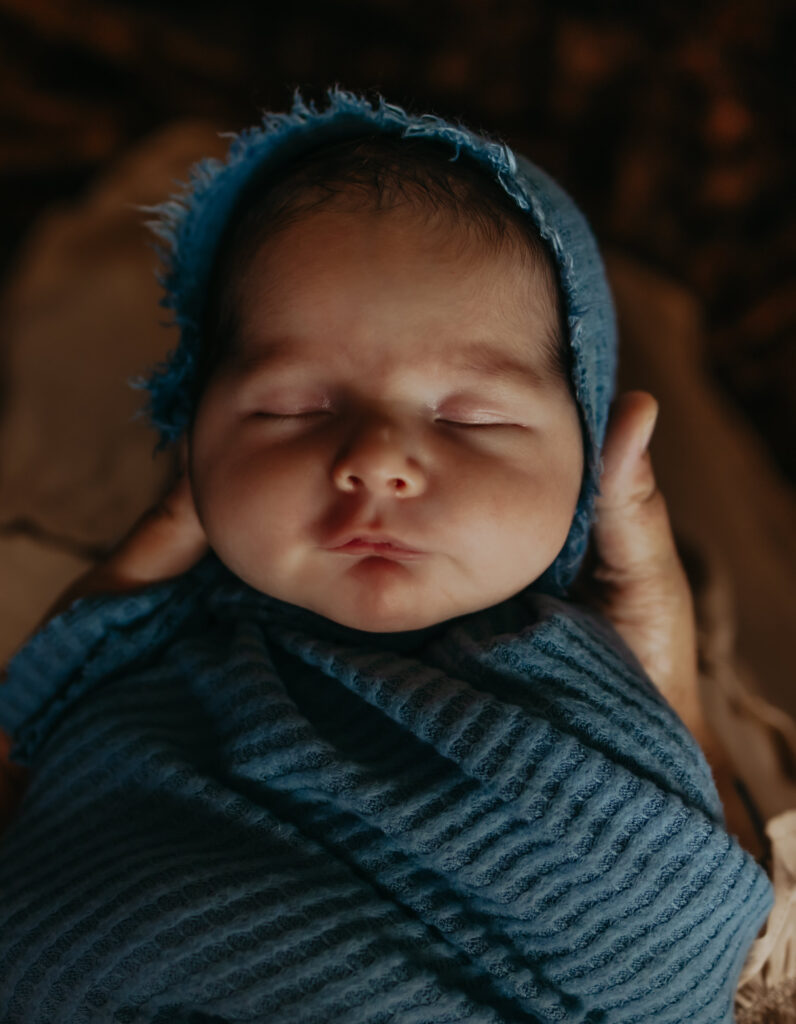 baby wrapped in blue blanket and hat during outdoor Edmonton newborn photo session