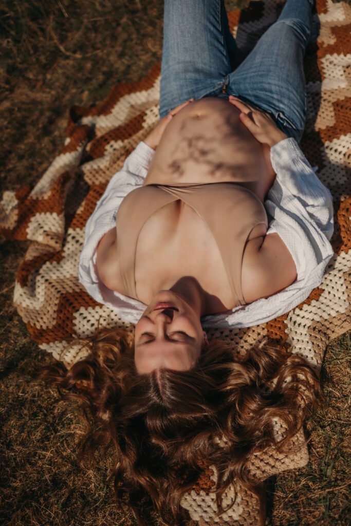 pregnant woman lays on a blanket outside for her Edmonton maternity photos
