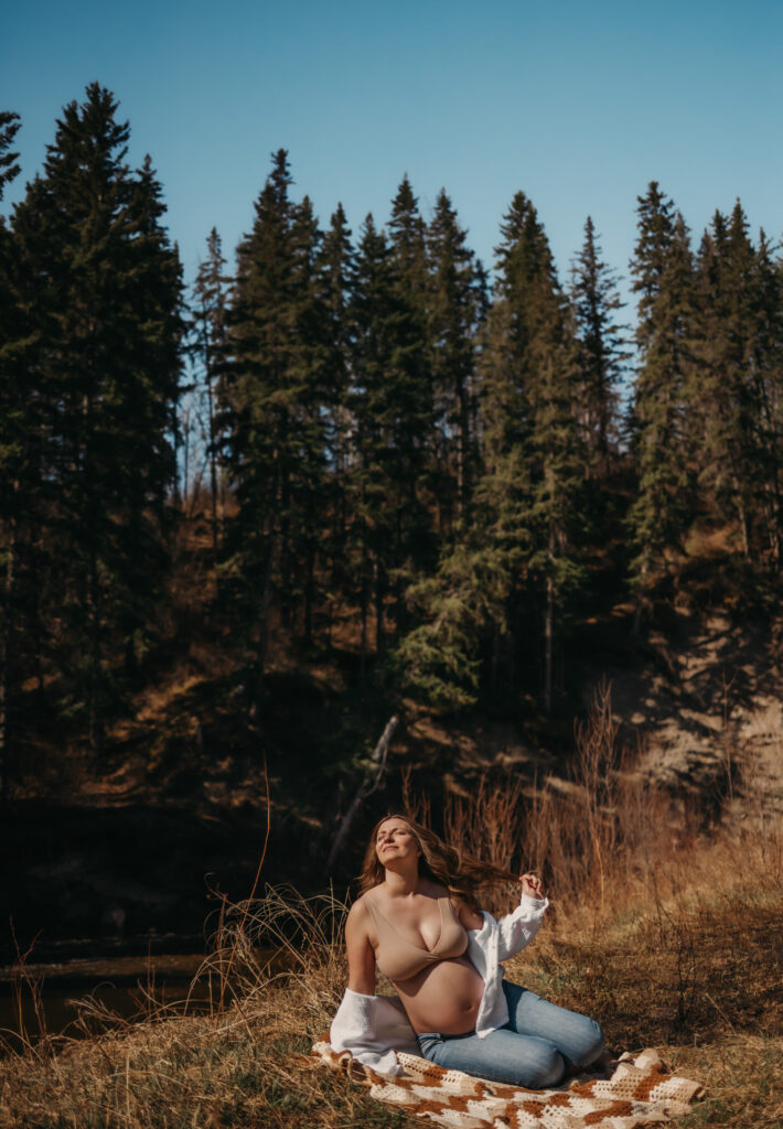 pregnant woman sits on a blanket outside for her Edmonton maternity photos