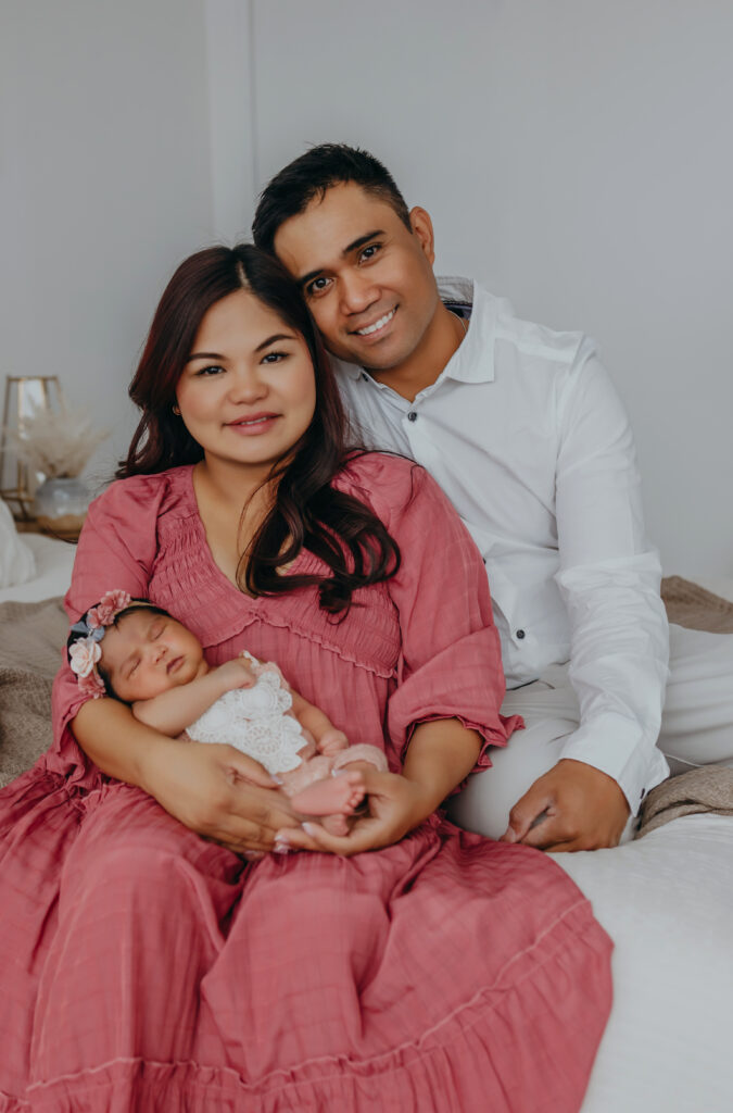 mom and dad and newborn sit during newborn photos in edmonton