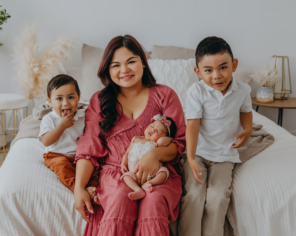 mom holds baby daughter and older kids during newborn photos in edmonton