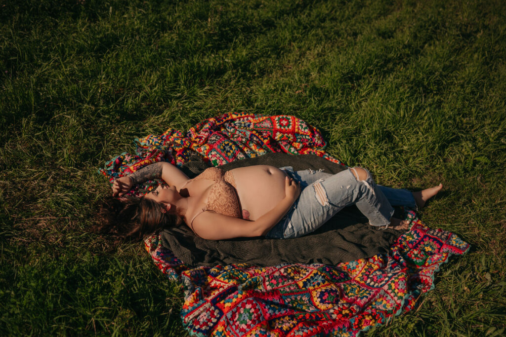 pregnant woman poses in jeans and bra during outdoor maternity photos in Edmonton