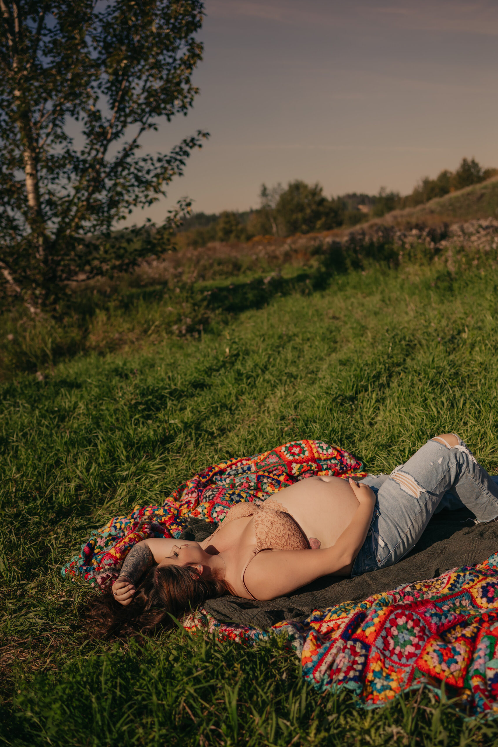 pregnant woman poses in jeans and bra during outdoor maternity photos in Edmonton