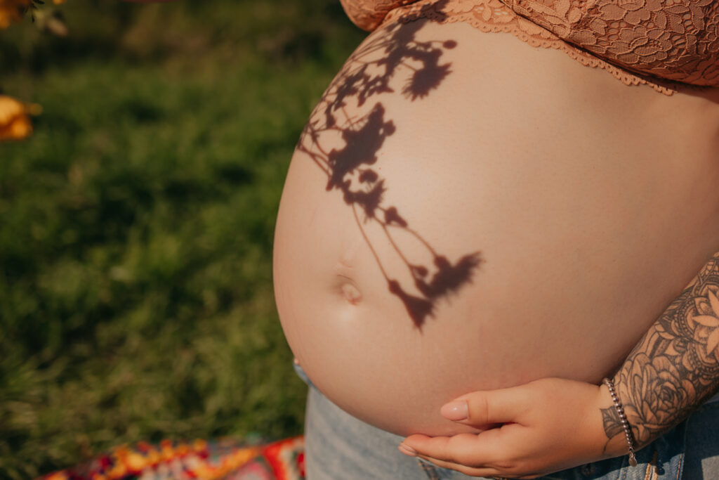 pregnant woman poses in jeans and bra during outdoor maternity photos in Edmonton