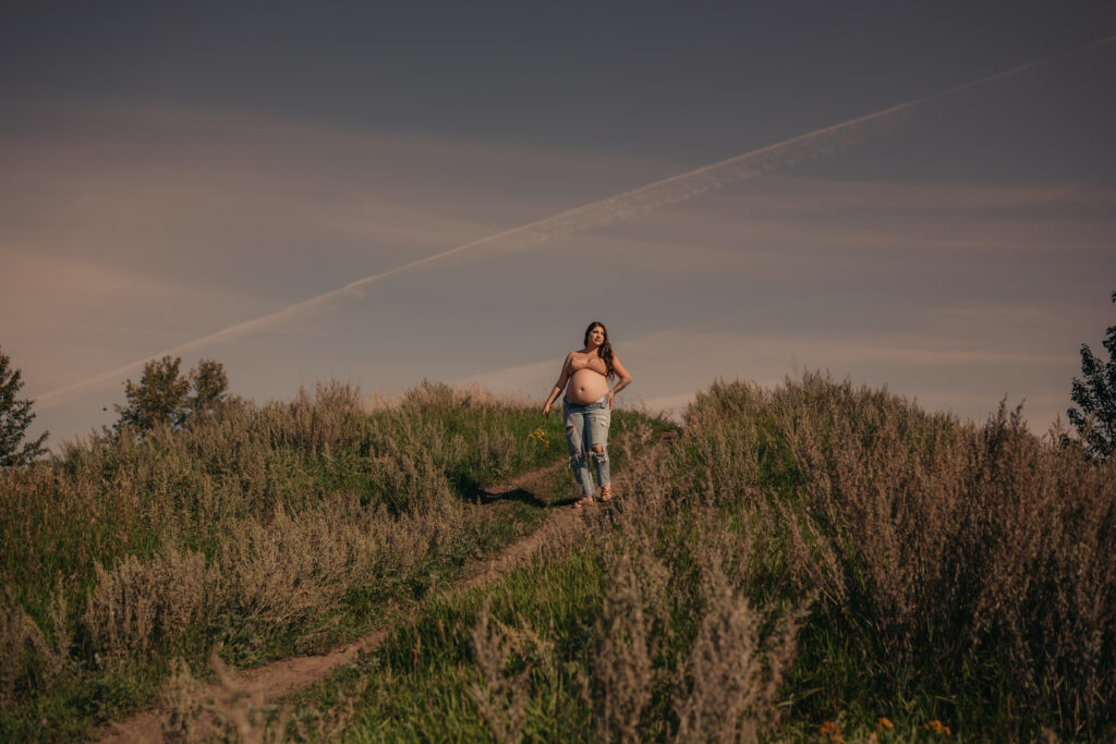 pregnant woman poses in jeans and bra during outdoor maternity photos in Edmonton