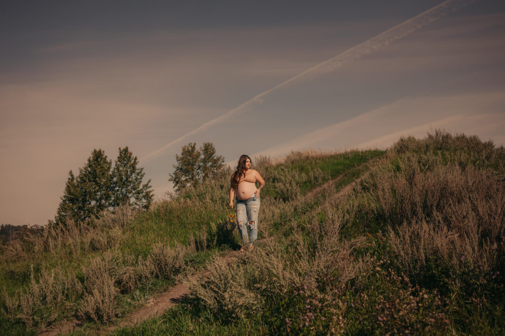 pregnant woman poses in jeans and bra during outdoor maternity photos in Edmonton