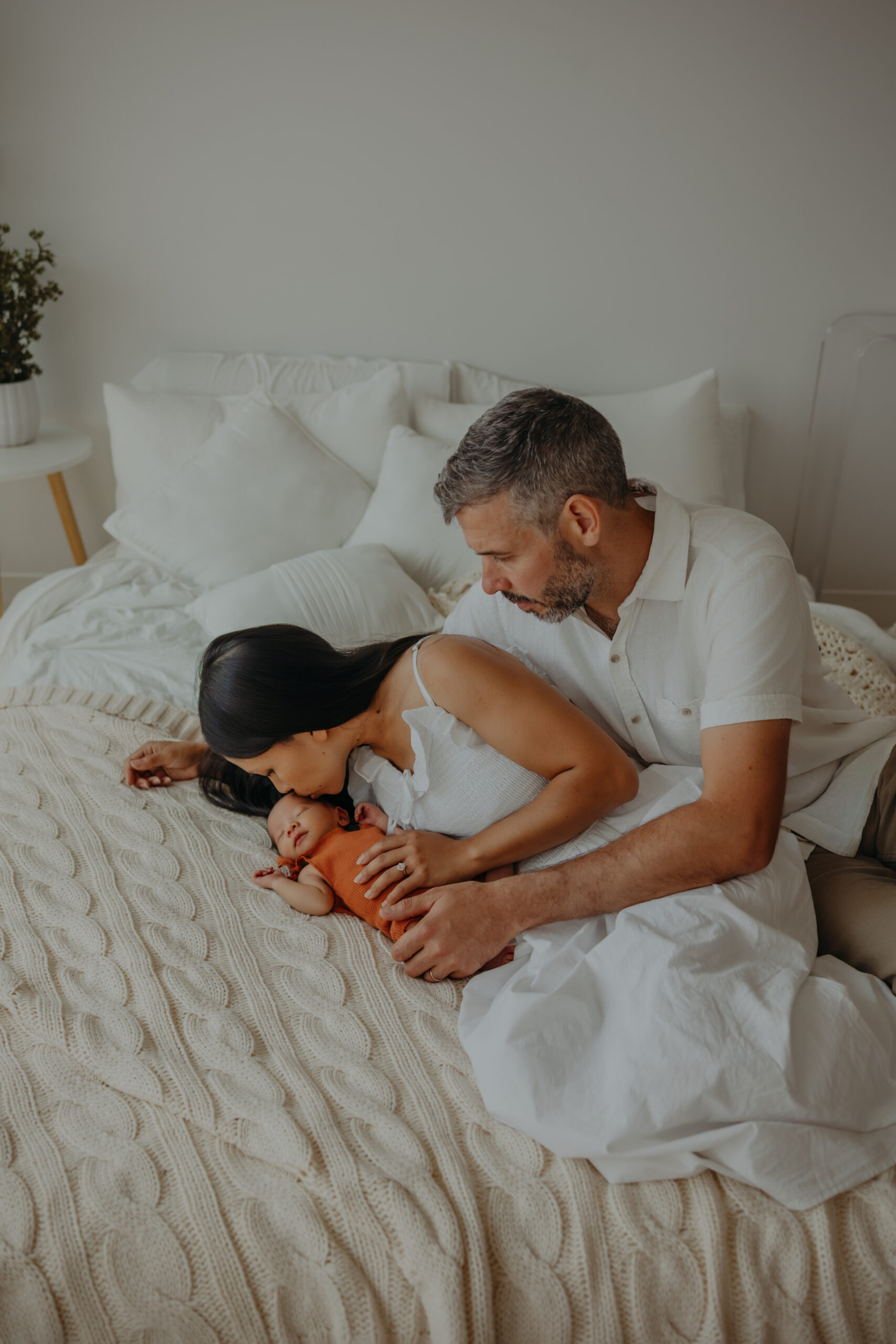 edmonton family poses for newborn photos, mom kisses baby