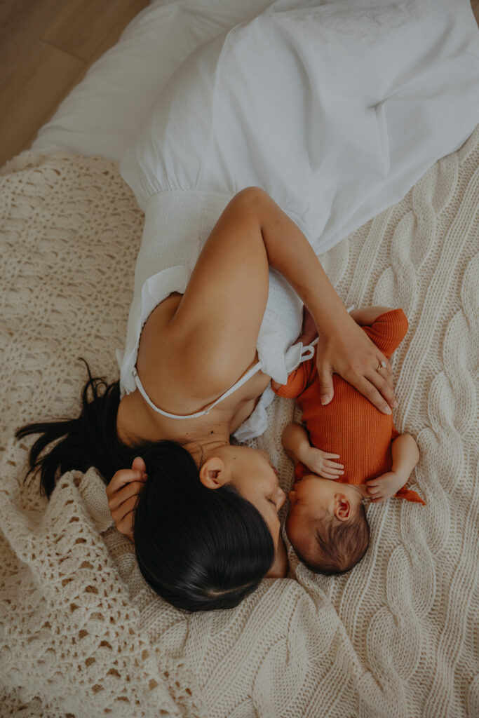 mom and baby on bed during newborn photos in edmonton