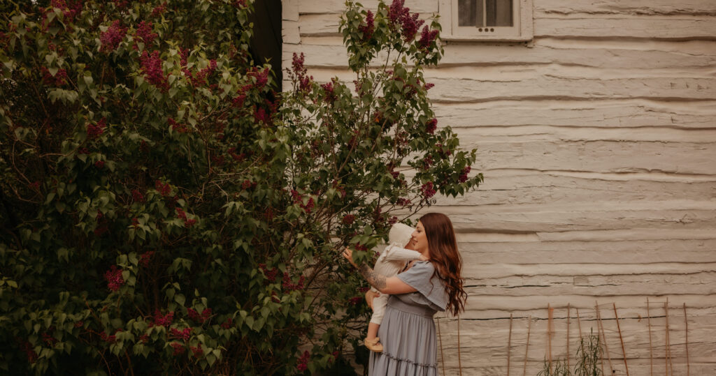 Mother holding her child during a connected spring family session in Edmonton lilac blossoms