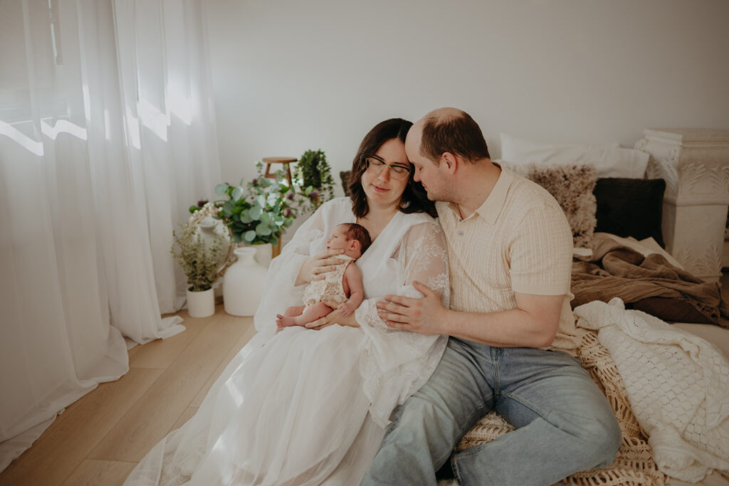 mom dad and baby embrace during newborn photos in edmonton
